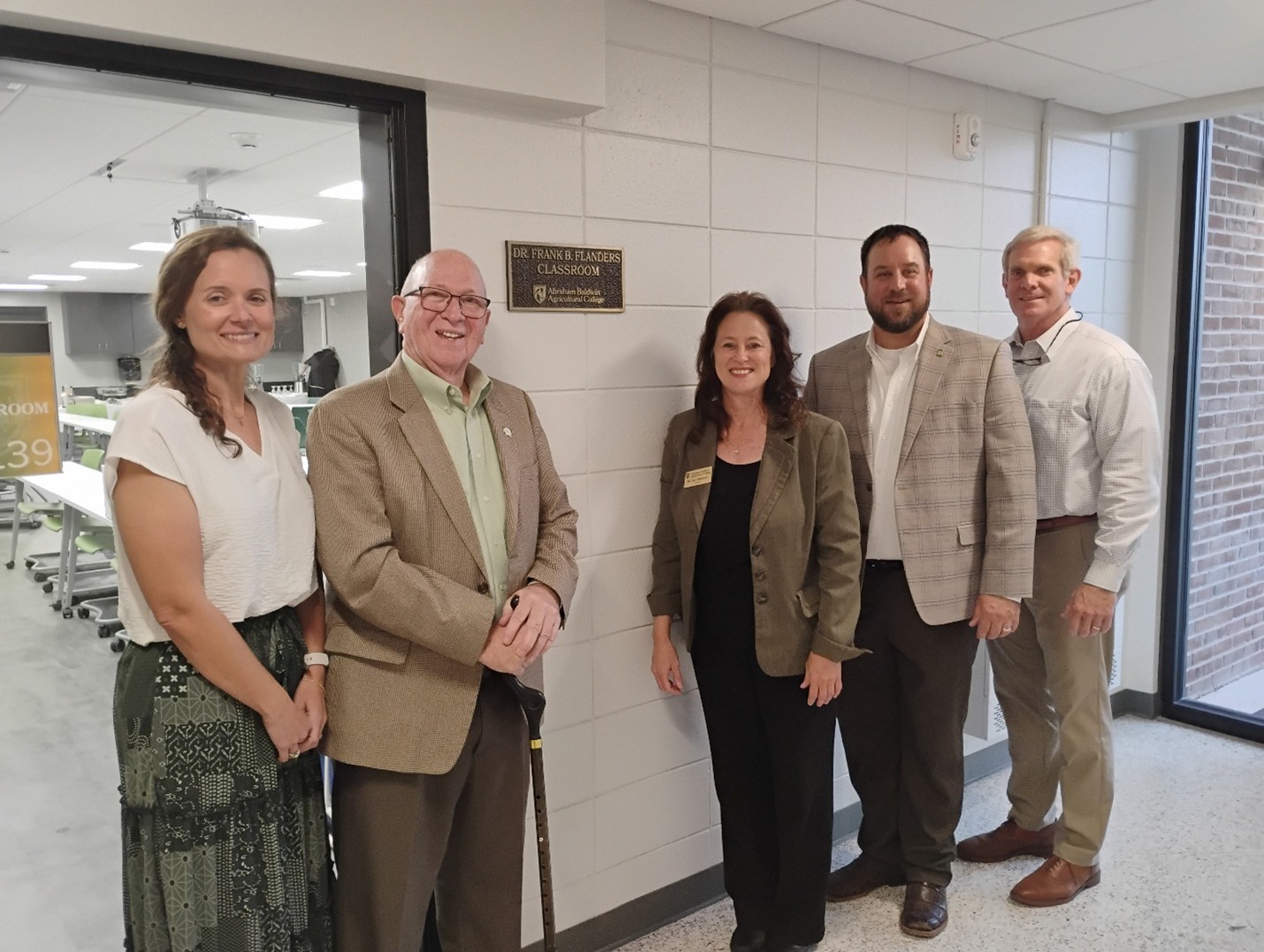 Dr. Frank Flanders stands proudly in front of the newly dedicated classroom bearing his name, a tribute to his lasting impact on education and the lives he’s touched. Also, pictured are (L-R) Dr. Sallie McHugh, Dr. Frank Flanders, President Tracy Brundage, Dr. Andrew Thoron, and Dr. Farish Mulkey