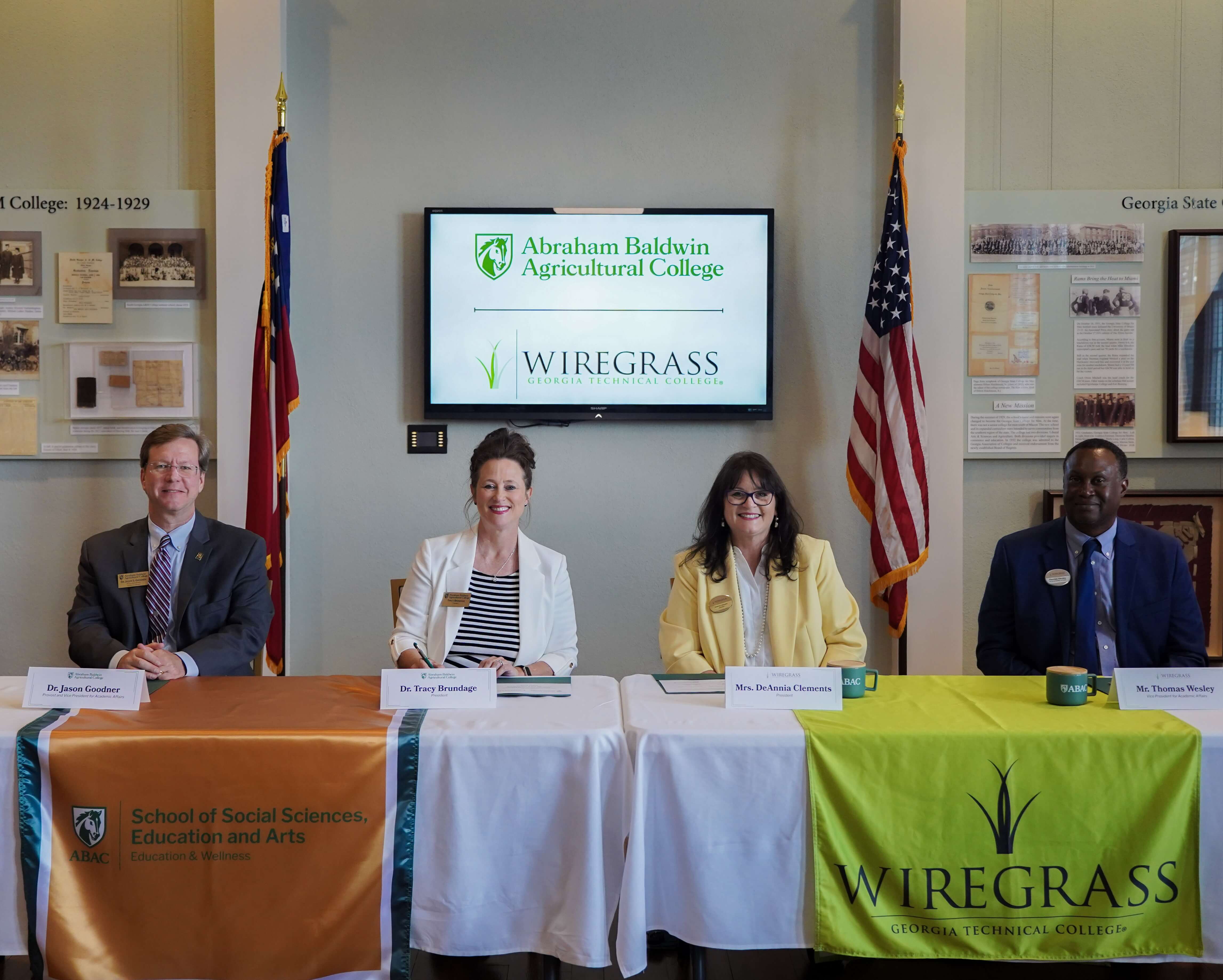 college officials at a table signing documents.