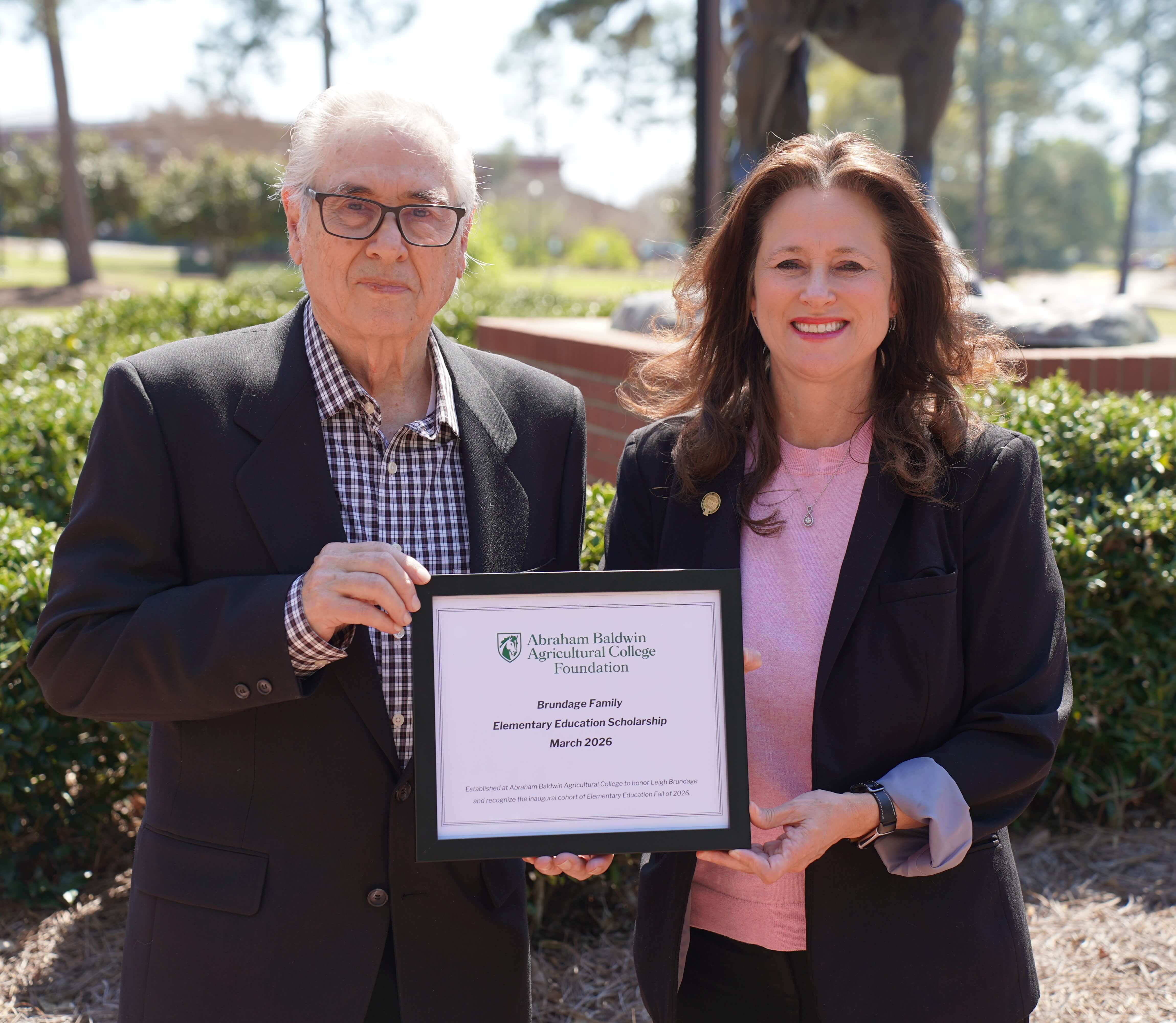 two people holding a certificate of a scholarship