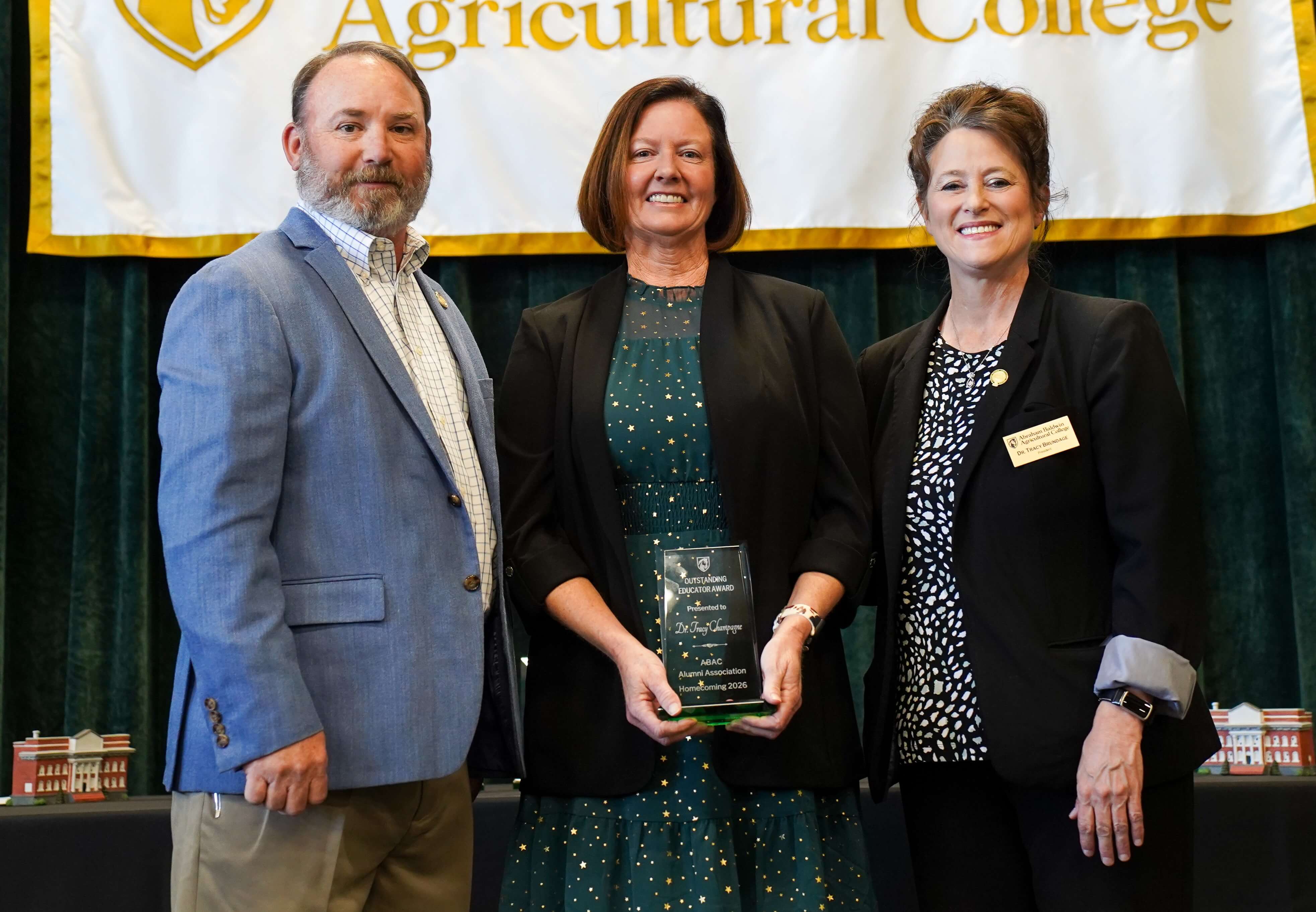 three people with the middle one holding a trophy.